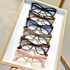 A display of vintage color block blue light blocking eyewear in a wooden frame.