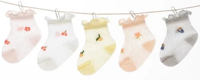 A pack of five thin summer casual baby socks in various pastel pink and white colors hanging on a line.