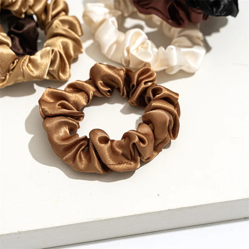 A close-up of a satin scrunchie in a golden brown color, showing its ruffled texture.