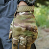 Une main portant des gants tactiques camouflage et une montre noire, tenue contre un fond sombre.