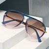 A pair of retro pilot sunglasses with gradient purple and pink lenses resting on a white surface.