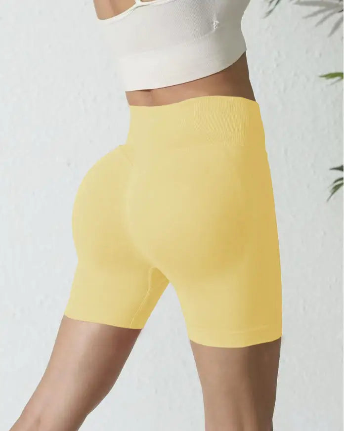 Une femme portant un short de yoga sans couture jaune taille haute et un haut blanc.