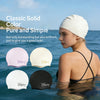 Una mujer con una gorra de natación blanca en el agua, con diversas gorras de silicona de colores expuestas cerca.