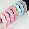 A set of colorful microfiber skincare headbands and wristbands in pastel shades arranged in a row.
