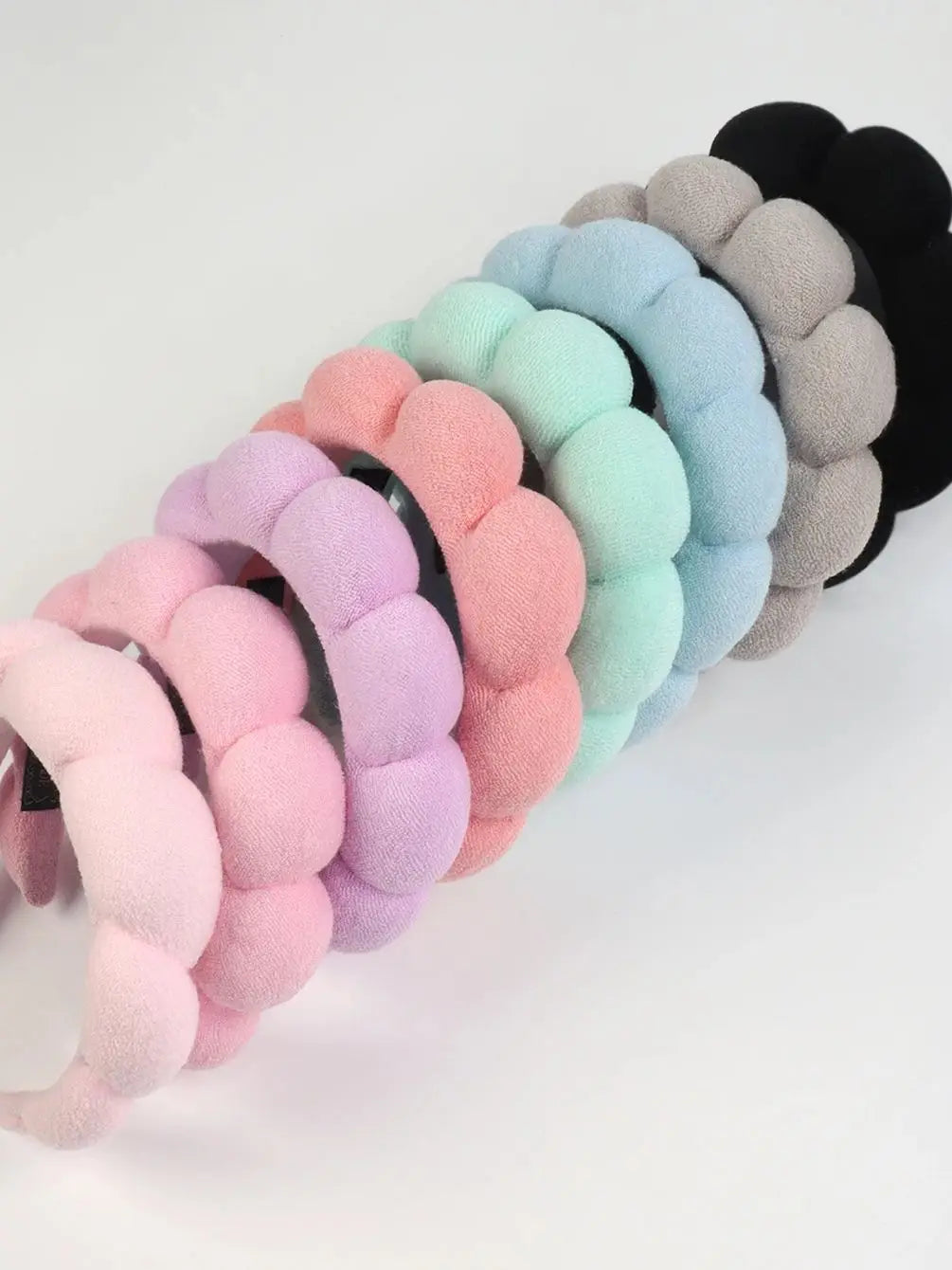 A set of colorful microfiber skincare headbands and wristbands in pastel shades arranged in a row.