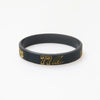 Black silicone wristband with gold lettering displaying 77 and a logo.