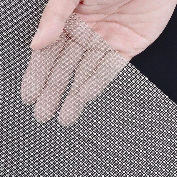 Una mano sostiene un par de guantes de malla de alambre beige claro contra un fondo de malla de alambre plateado.
