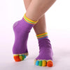 Purple rainbow yoga socks worn on a foot, showing multi-colored stripes and toe accents.