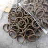 A pile of 50 pieces of mixed color elastic hair bands lying on a gray surface.