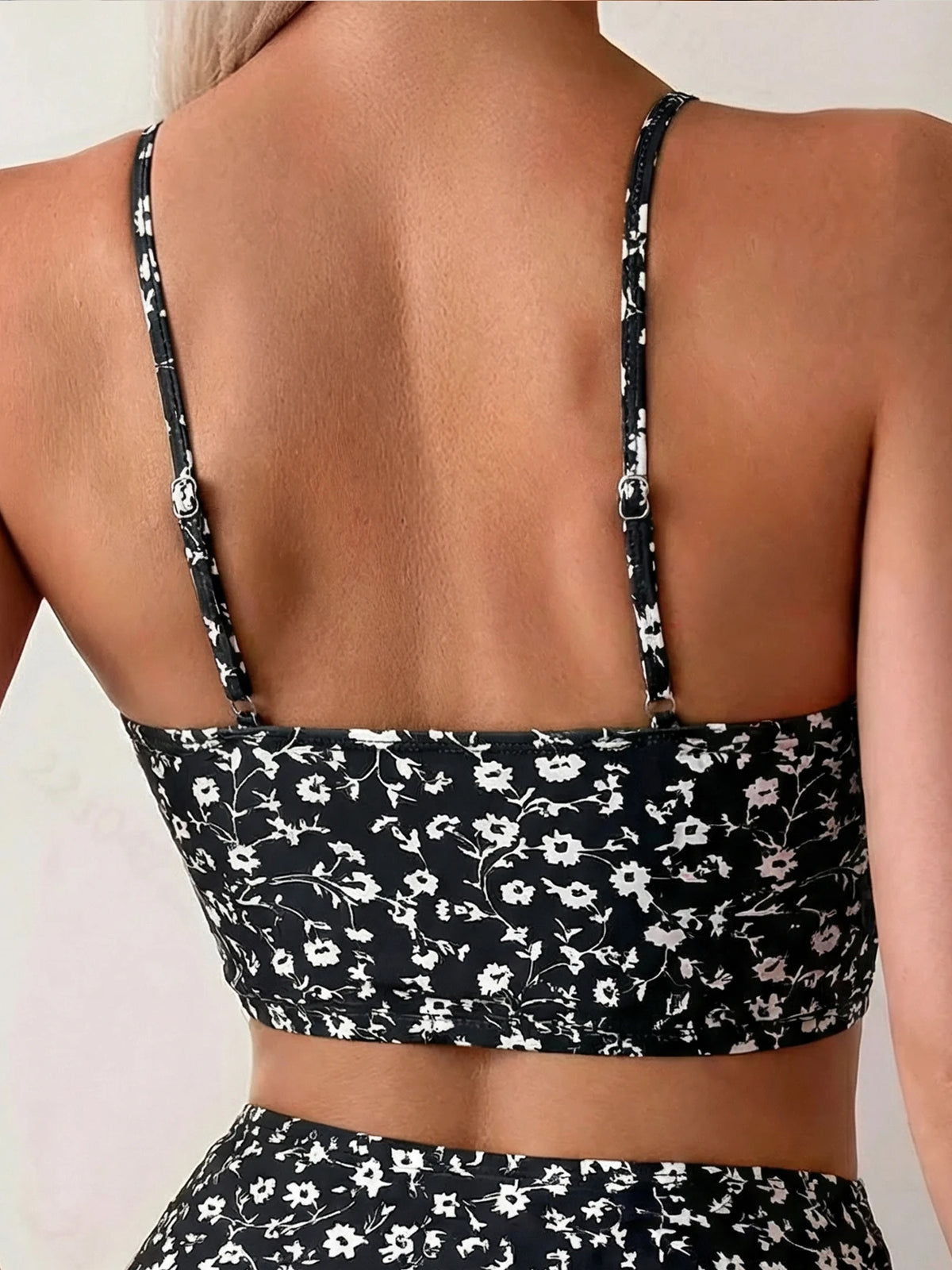 Mujer vistiendo un bikini de dos piezas bohemio con estampado floral blanco y negro, vista desde atrás.