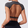 A woman wearing a dark gray women's fitness crop top yoga and gym t-shirt, shown from the back.