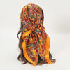 An orange and red paisley satin square scarf tied around a dark hair, ready for use as a hijab.