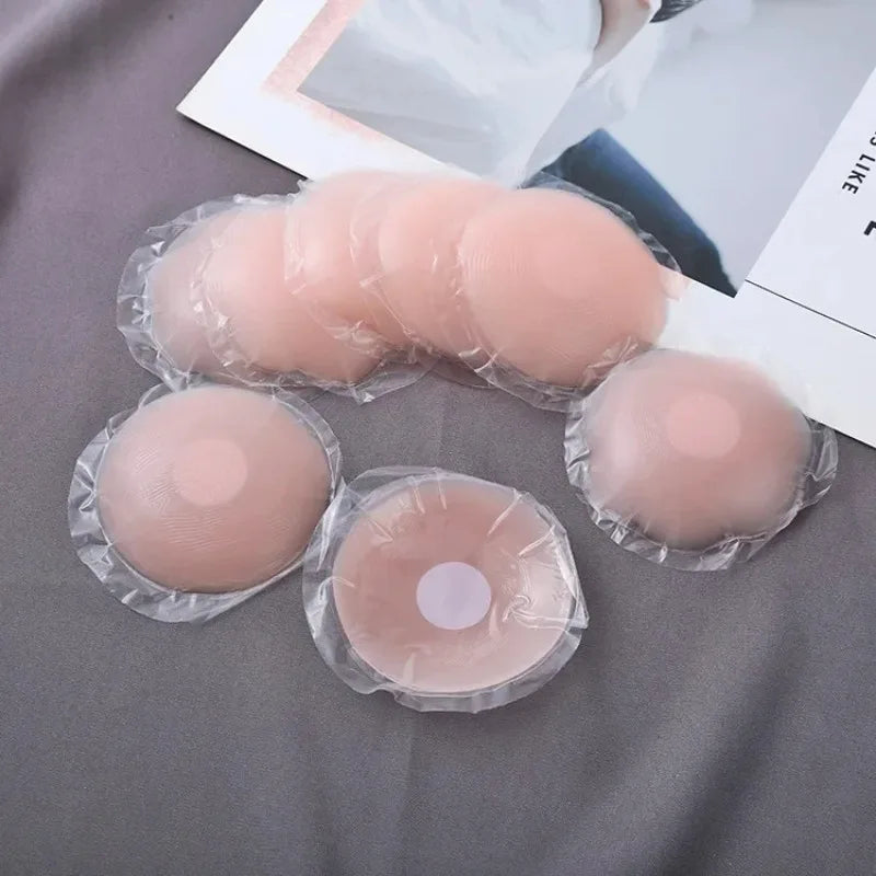 Un ensemble de cache-lèvres en silicone réutilisables de couleur pêche translucide sont disposés sur un tissu gris.