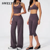 A woman models a dark purple women's premium fitness tracksuit consisting of a sports bra top and leggings.