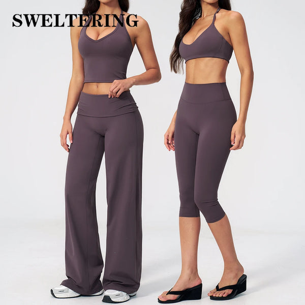 A woman models a dark purple women's premium fitness tracksuit consisting of a sports bra top and leggings.