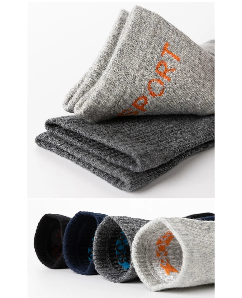 A stack of gray and dark gray men's sport compression socks rolled up for display.