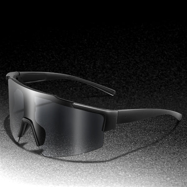 A pair of black cycling sunglasses with a flexible frame and curved lenses resting on a dark surface.