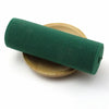 A dark green elastic band rolled up, resting on a light wooden plate.