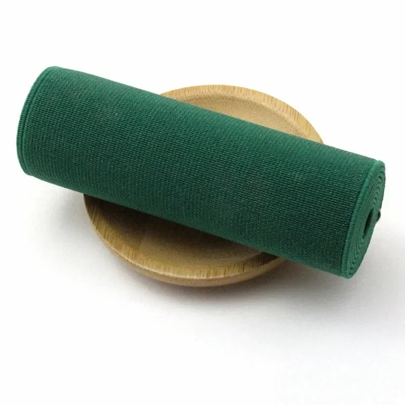 A dark green elastic band rolled up, resting on a light wooden plate.