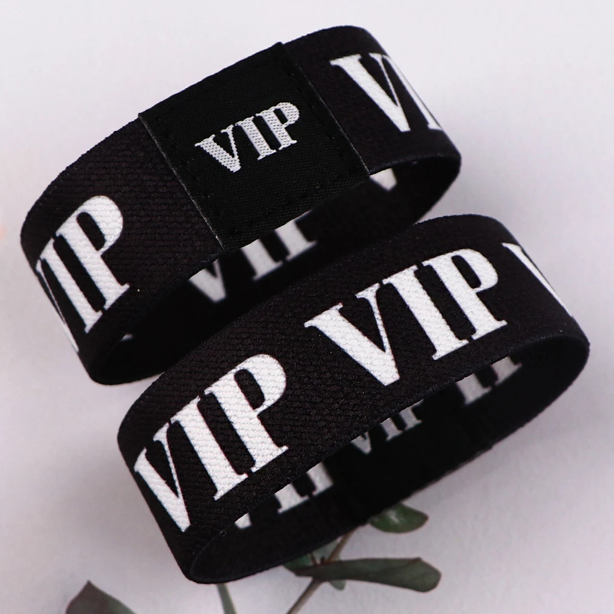Schwarze Acryl-Elastikarmbänder mit weißer VIP-Beschriftung auf weißem Hintergrund.