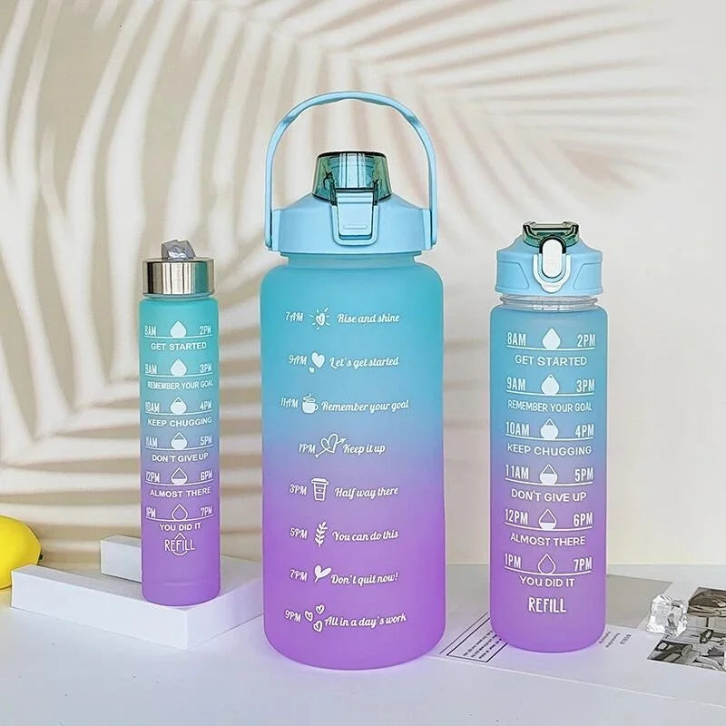 Un juego de tres botellas deportivas con degradado azul y morado y pajitas, mostradas sobre una superficie blanca.