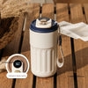 A white thermo mug with a black lid and digital display sits on a wooden surface.
