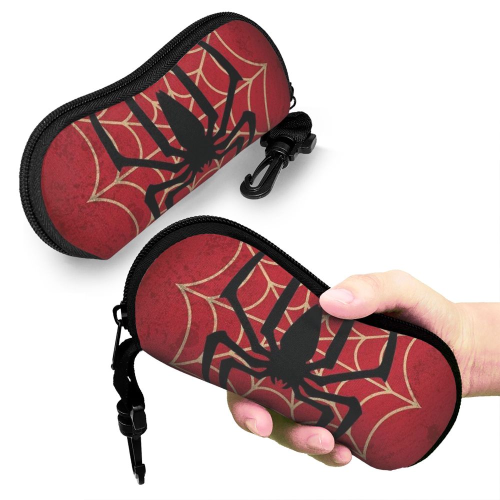 A red spider web patterned pouch for eyeglasses being held by a hand.
