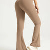 A person wearing beige high-waisted bootcut yoga pants is shown in a side view.