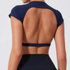 A woman wearing a navy blue women's fitness crop top yoga and gym t-shirt, shown from the back.