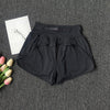 Black high-waist yoga and fitness shorts laid flat on a dark gray textured surface.