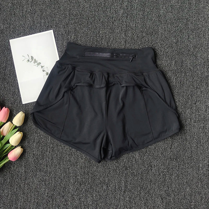 Black high-waist yoga and fitness shorts laid flat on a dark gray textured surface.