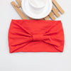 Ein leuchtend rohes Haarband oder Scrunchie neben einer weißen Untertasse und Holzstäbchen.