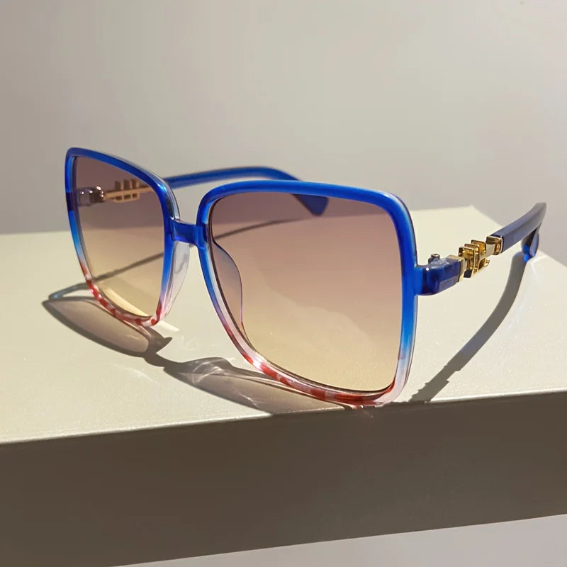 Retro two-tone gradient sunglasses with blue frames and gradient lenses resting on a white surface.