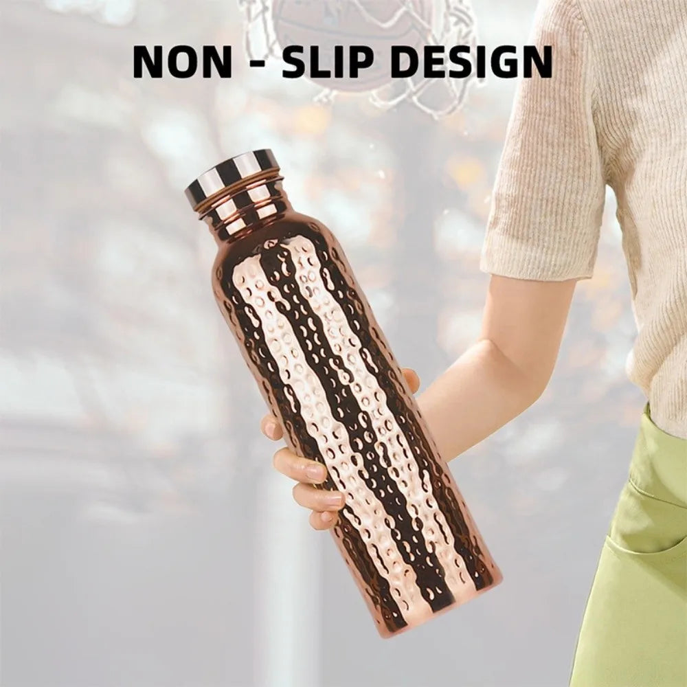 A hand holds a brown copper insulated water bottle with a textured anti-slip design.