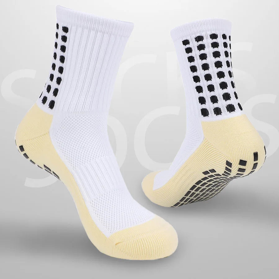 Ein Paar weiße sportliche Grip-Socken mit gelben Akzenten und schwarzen Polka Dots, von der Seite gezeigt.