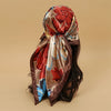 A brown satin square scarf with a floral pattern is tied around dark hair.