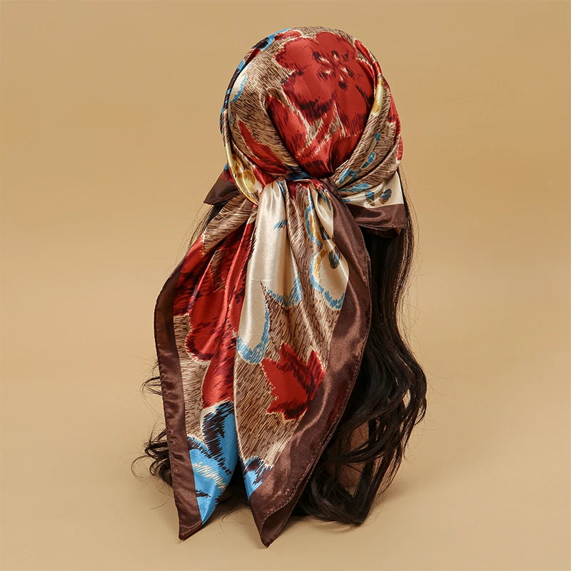 A brown satin square scarf with a floral pattern is tied around dark hair.