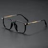 A pair of black retro anti-blue light glasses with gold accents resting on a dark surface.