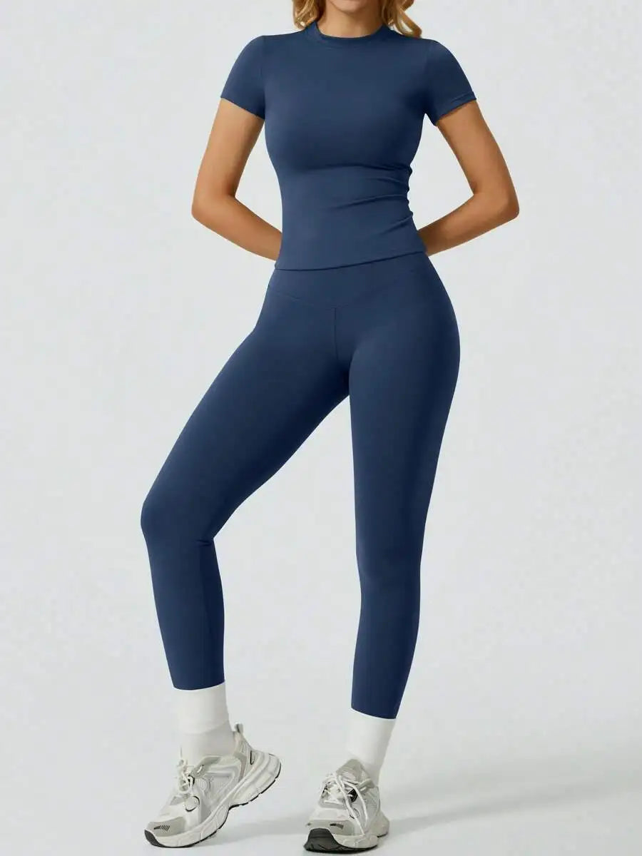 Eine Frau trägt ein dunkelblaues Yoga-Set mit hohen Bund-Leggings und einem kurzärmeligen Oberteil.