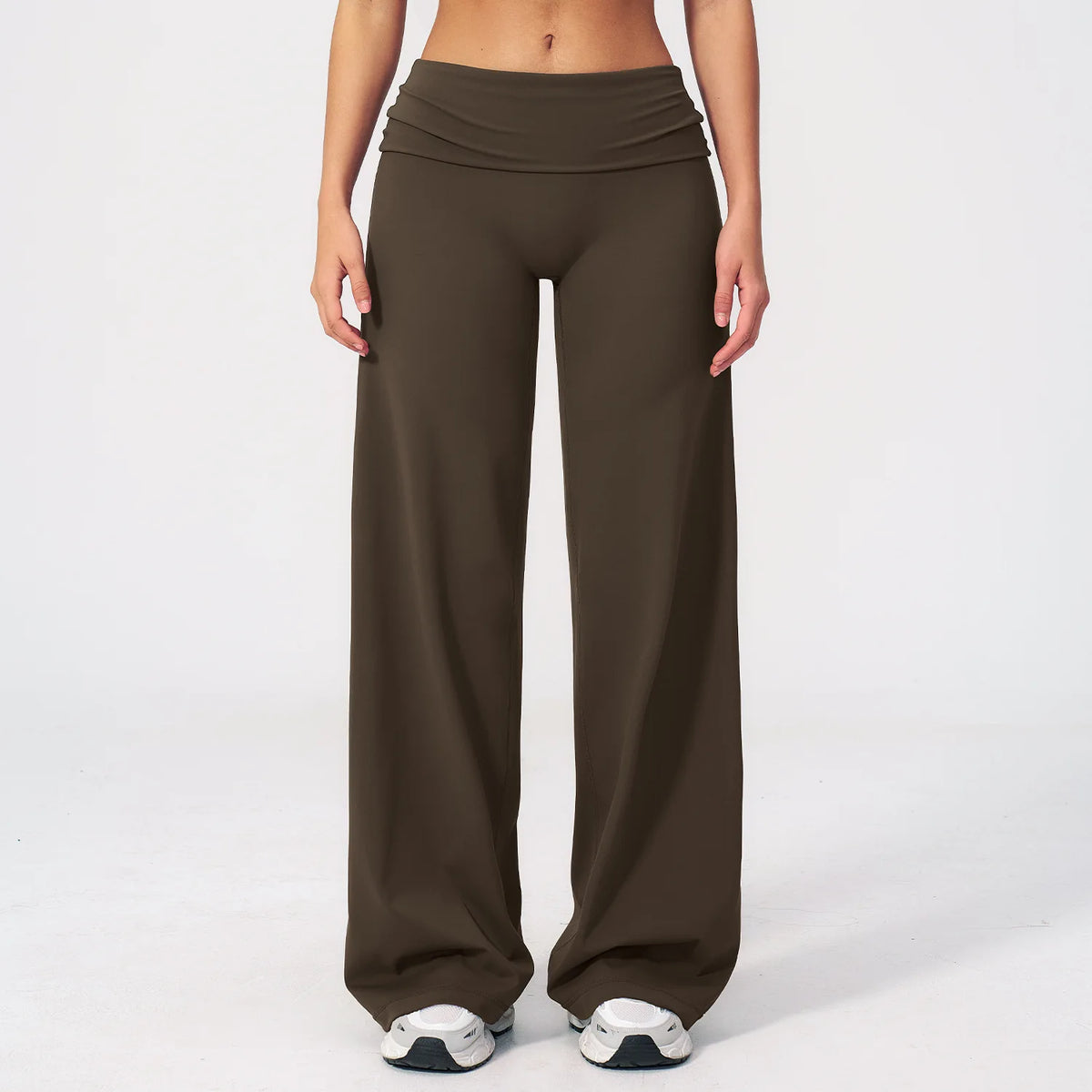 A model is wearing dark brown flared high-waist yoga pants with white and gray athletic shoes.