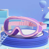 Pink swimming goggles for children resting on a blue circular platform with a light blue background and a purple balloon.