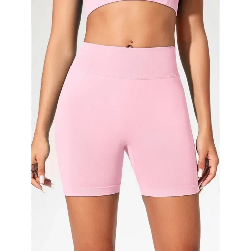 A model is wearing light pink high-waisted yoga shorts.