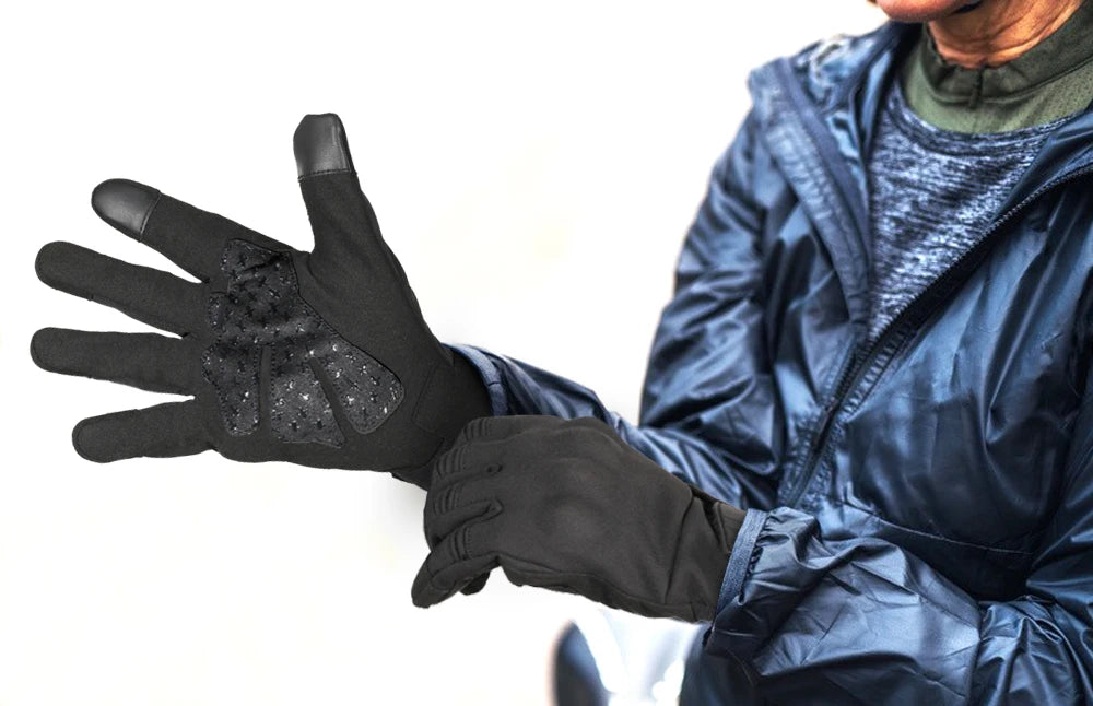 A person wearing black motorcycle riding gloves is holding their hand out, showing the textured palm.
