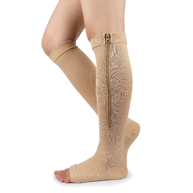 A close-up of beige compression stockings with a zipper on the calf, worn on a bare foot.