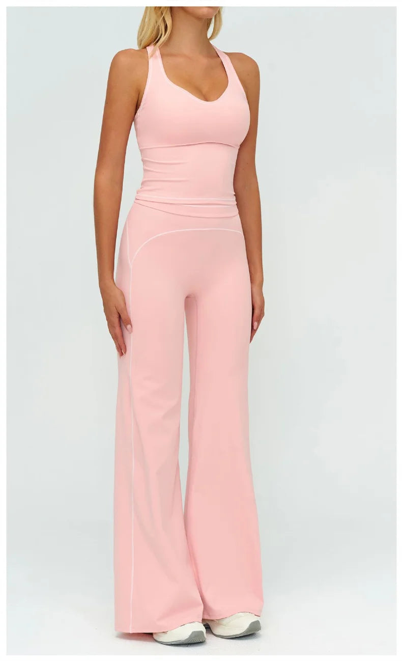 Una mujer modela un conjunto deportivo de yoga rosa claro de talle alto con pantalones largos y una parte superior a juego.