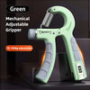 A green mechanical adjustable gripper hand strengthener with a coiled spring and weight markings is shown on a dark surface.