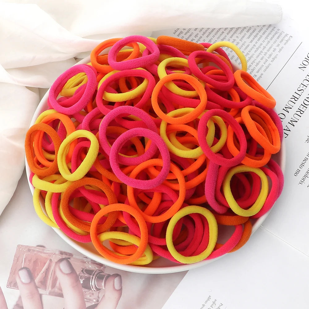 A plate filled with 50 pieces of mixed color elastic hair bands in pink, orange, and yellow.