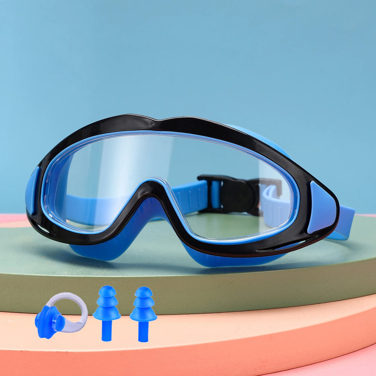 A pair of blue swimming goggles with black frames and a small set of blue plastic tree-shaped items are displayed on a light 