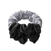 A headband featuring two sections of satin fabric, one silver and one black.
