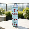 A light blue reusable water bottle with a cherry pattern sits on a white table outdoors.